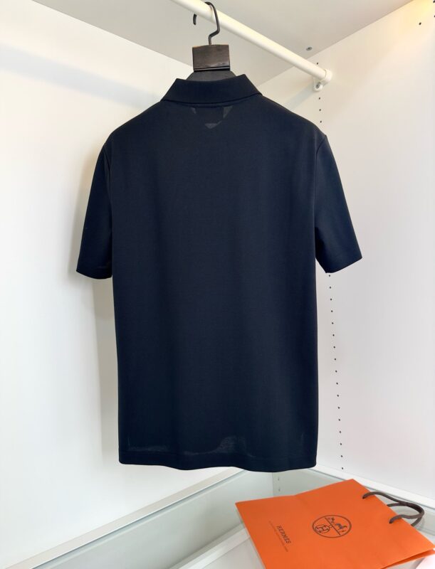 Maglietta polo navy blu su gruccia con borsa arancione minimalista, stile casual elegante.