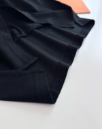 Tessuto nero lucido con dettaglio di colore arancione, elegante e sofisticato.