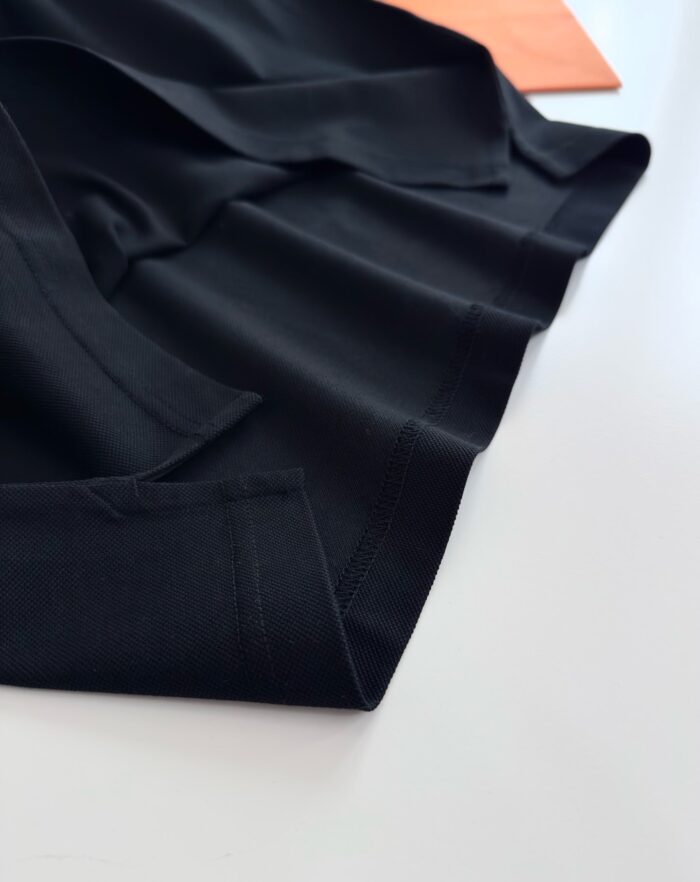 Tessuto nero lucido con dettaglio di colore arancione, elegante e sofisticato.