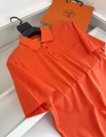 Maglietta polo arancione elegante con borsa di lusso, stile casual e raffinato.