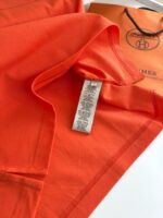 Maglietta arancione di qualità con etichetta e confezione elegante, stile vivace e moderno.