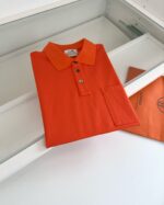 Maglietta polo arancione, stile classico, in esposizione minimalista e moderna.