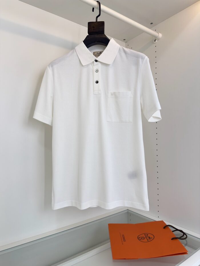 Maglietta polo bianca elegante con dettagli neri e borsa arancione, stile moderno e sofisticato.