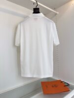 Poloshirt bianco di alta qualità con logo, elegante e minimalista, accompagnato da shopping bag arancione.