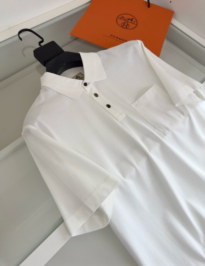 Camicia bianca elegante su appendiabiti con borsa arancione, stile casually raffinato e versatile.