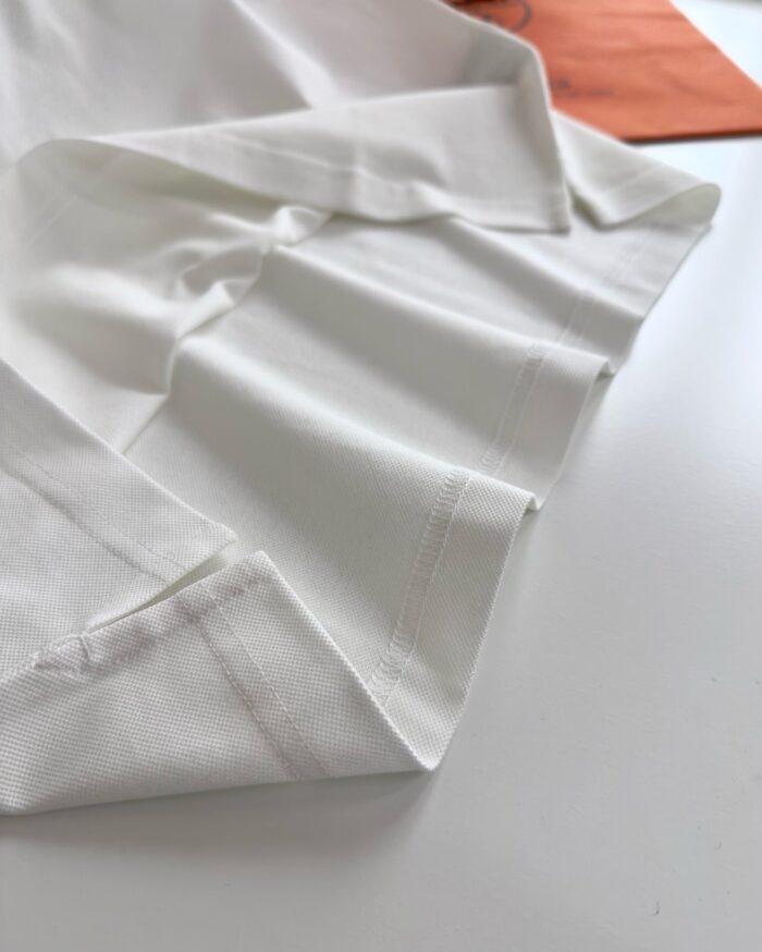 Tessuto bianco elegante con dettagli arancioni e texture morbida, ideale per moda e design.