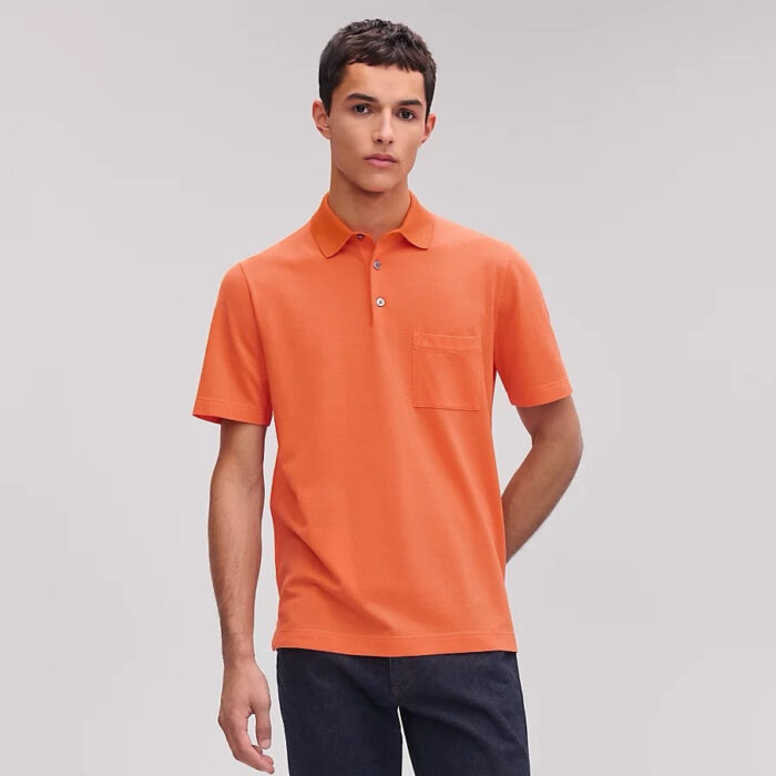 Giovane uomo in polo arancione casual e moderno, stile confidente e giovane.
