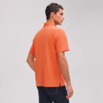 Uomo con polo arancione casual moderno, stile relaxed e abbigliamento estivo elegante.