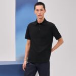 Modello uomo con polo nera in sfondo minimalista, stile moderno e look casual elegante.