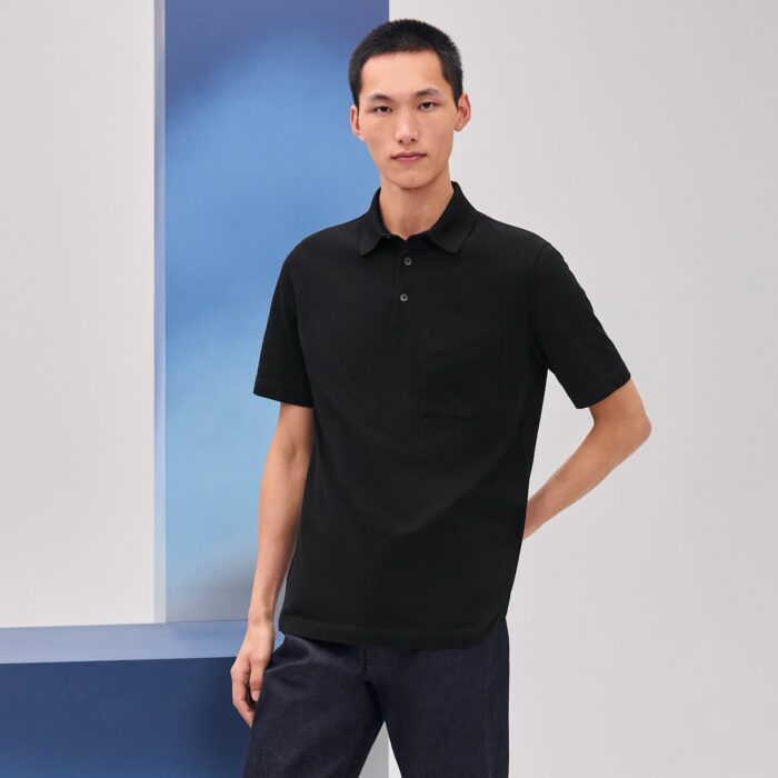 Modello uomo con polo nera in sfondo minimalista, stile moderno e look casual elegante.