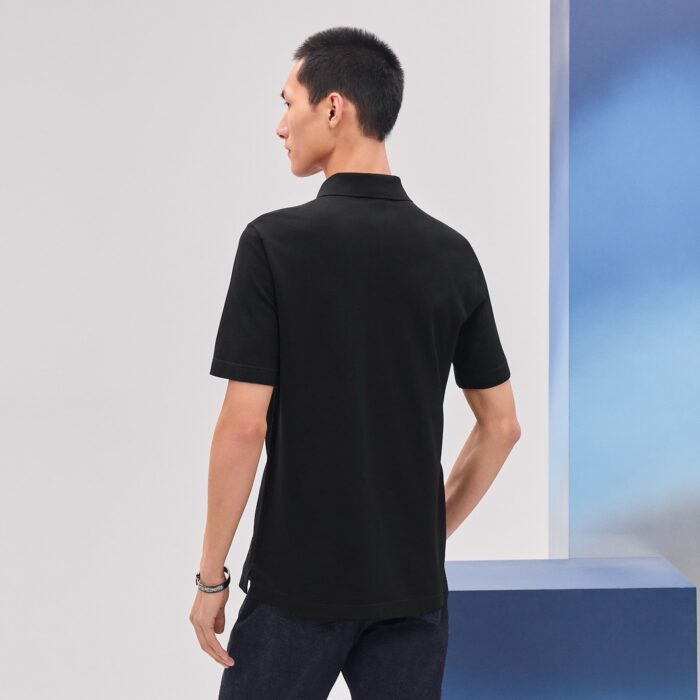 Uomo in polo nero in sfondo minimalista e moderno.