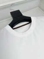T-shirt bianca minimalista su gancio nero, semplice ed elegante, perfetta per ogni stile casual.
