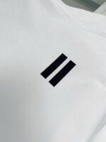 Maglietta bianca con logo minimalista a due barre nere, stile moderno e versatile.
