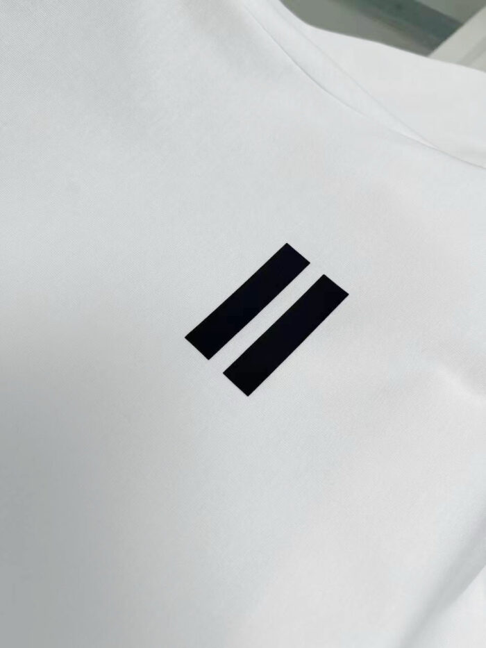 Maglietta bianca con logo minimalista a due barre nere, stile moderno e versatile.