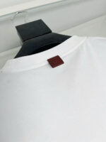 T-shirt bianca con particolare in pelle sul retro del collo, stile minimalista e versatile.