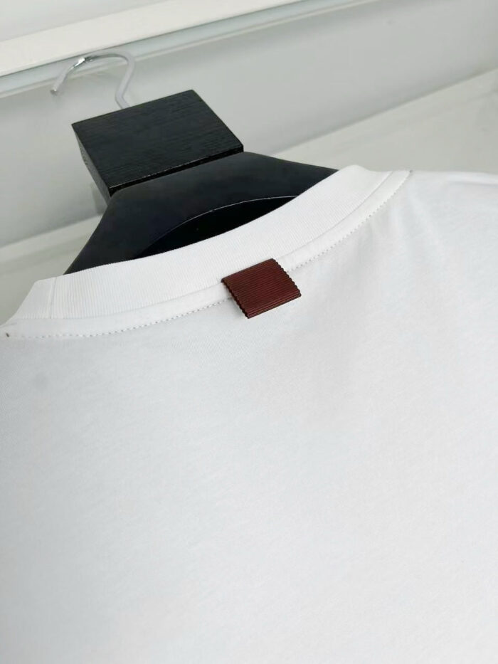 T-shirt bianca con particolare in pelle sul retro del collo, stile minimalista e versatile.