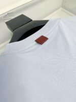 Maglietta celeste con etichetta in pelle, girocollo, stile casual e elegante.