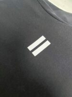 Maglietta sportiva con logo minimalista a linee bianche su sfondo scuro elegante.