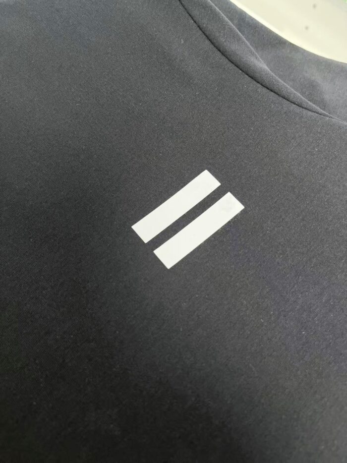 Maglietta sportiva con logo minimalista a linee bianche su sfondo scuro elegante.