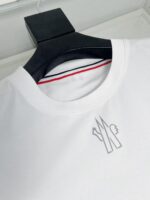 Maglietta bianca con logo stilizzato, dettaglio colorato e stile casual e moderno.