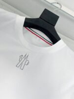 T-shirt bianco con ricamo minimalista e dettaglio colorato sul colletto, stile moderno e versatile.