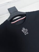 Maglietta nera con logo bianco, colletto con dettaglio colorato, stile minimalista e moderno.