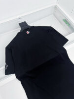 T-shirt nera minimalista con logo discreto e dettagli eleganti in contesto boutique raffinato.