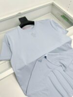 T-shirt blu chiaro casual con logo sottile, semplice ed elegante, su supporto nero minimalista.