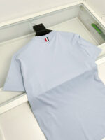 Maglietta azzurra con dettaglio a righe rosso, bianco e blu, stile casual e moderno.