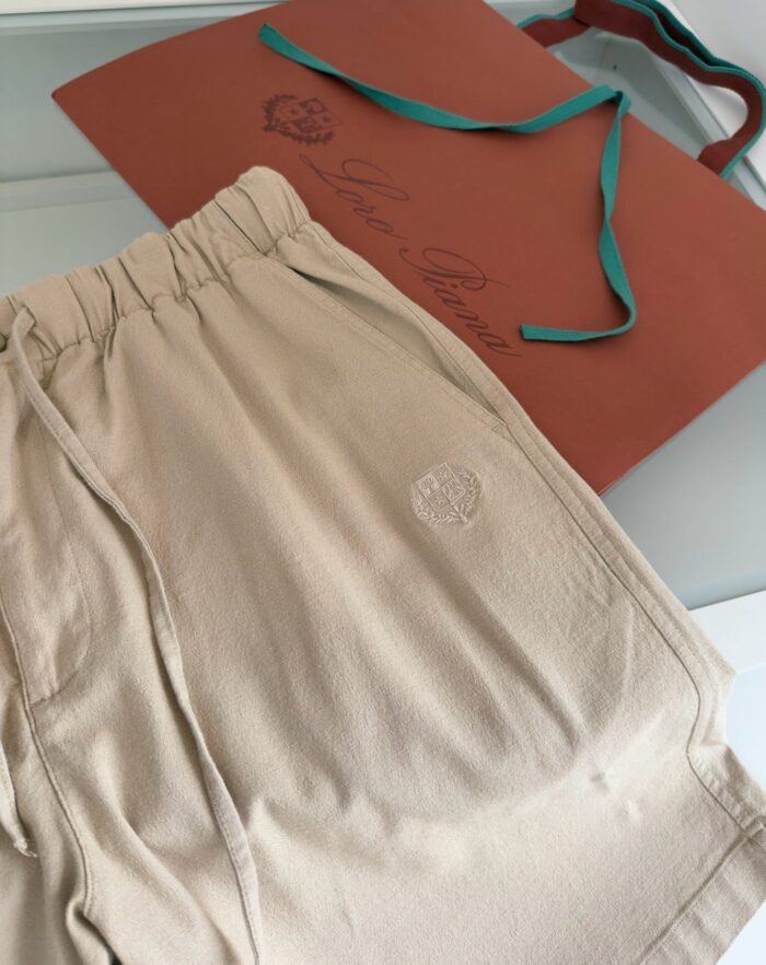 Shorts beige casual, regalo di lusso con confezione elegante e dettaglio di fiocco azzurro.