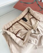 Pantaloni beige casual con elastico, elegante packaging in sfondo, stile semplice e versatile.