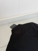 Maglietta nera elegante con collo strutturato, tessuto leggero e taglio raffinato.