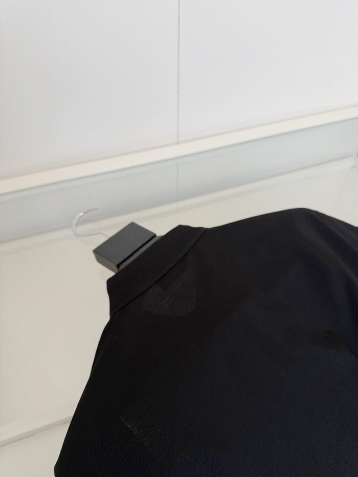 Maglietta nera elegante con collo strutturato, tessuto leggero e taglio raffinato.