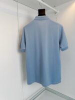 Camicia polo celeste da uomo in cotone, stile casual elegante, mostra sul retro su appendiabiti nero.