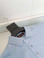 Maglietta polo azzurro chiaro elegante su gancio nero, stile classico e dettaglio raffinato