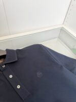 Maglietta polo navy blu elegante con logo ricamato, dettagli raffinati e texture moderna.