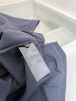 Maglietta in jersey navy con etichetta di cura e stile minimalista.