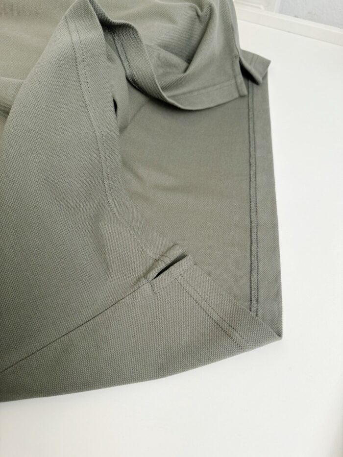 Dettaglio di tessuto verde oliva, elegante, con cucitura e piega impeccabili, stile moderno e versatile.