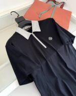 Polo nera elegante con colletto bianco, logo ricamato e zip frontale, stile sofisticato.