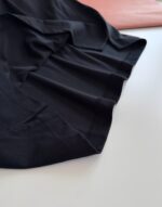 Tessuto nero elegante con dettagli di tessuti rosa chiaro, stile sofisticato e contrasto di texture.