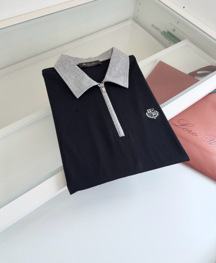 Maglietta polo nera con colletto grigio, zip frontale e logo ricamato, stile moderno ed elegante.