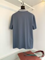 Maglietta polo blu con colletto a contrasto e accessorio in vino, stile casual elegante.