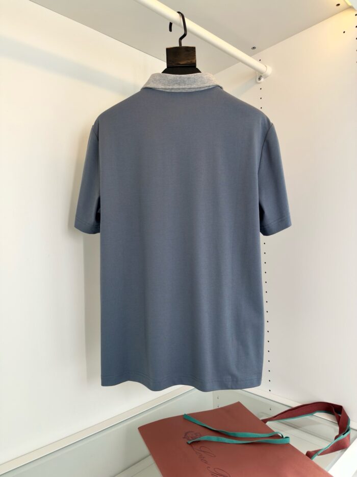 Maglietta polo blu con colletto a contrasto e accessorio in vino, stile casual elegante.