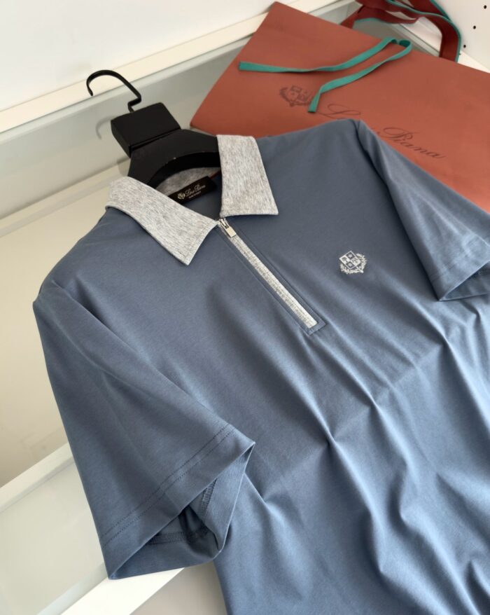 Maglietta polo blu con colletto bianco, dettagli eleganti e stile sofisticato in esposizione raffinata.