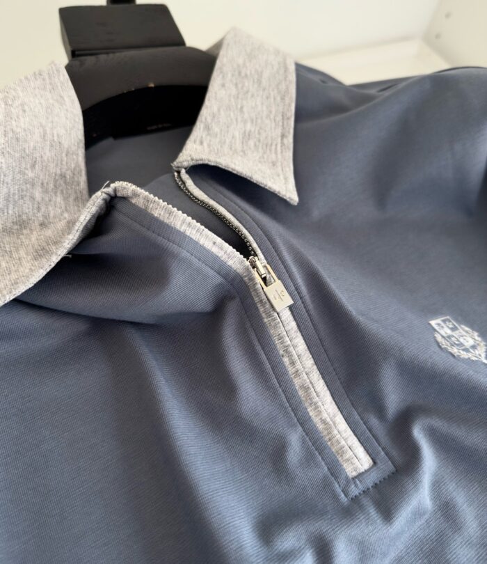 Maglietta polo moderna con colletto grigio, zip e logo ricamato, perfetta per sport e casual.