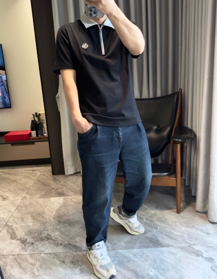 Stile casual moderno con polo nero, jeans chiari e ambiente living contemporaneo elegante.