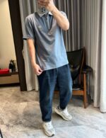 Ragazzo in polo e sneakers si specchia in ambiente moderno e accogliente.