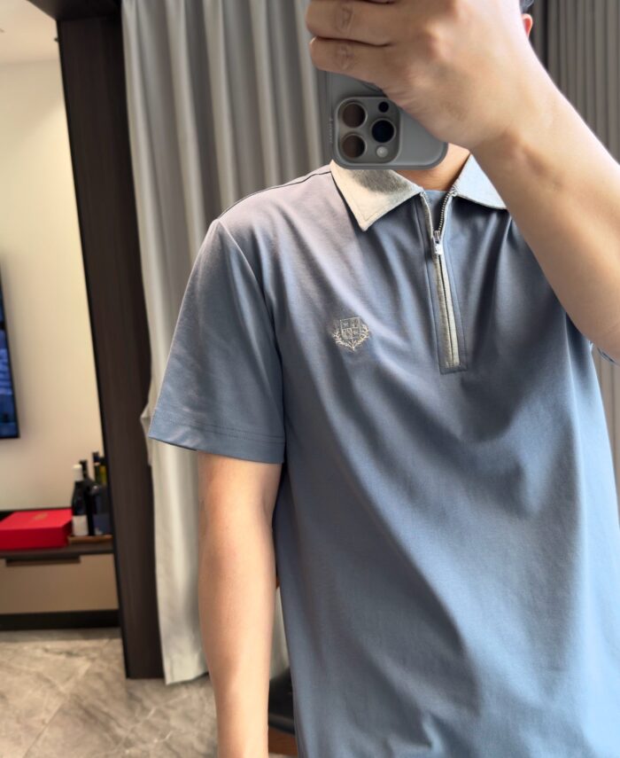 Look casual con polo blu, collo bianco e dettaglio logo in ambiente moderno.