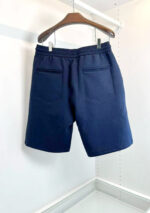 Pantaloncini navy classici in tessuto cotone, eleganti e versatili, su appendiabiti in legno.