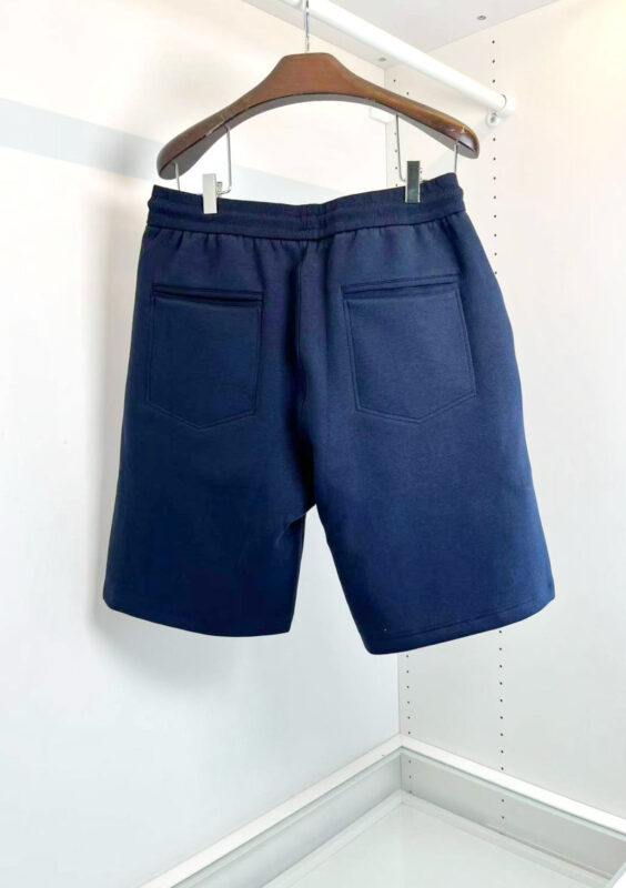 Pantaloncini navy classici in tessuto cotone, eleganti e versatili, su appendiabiti in legno.
